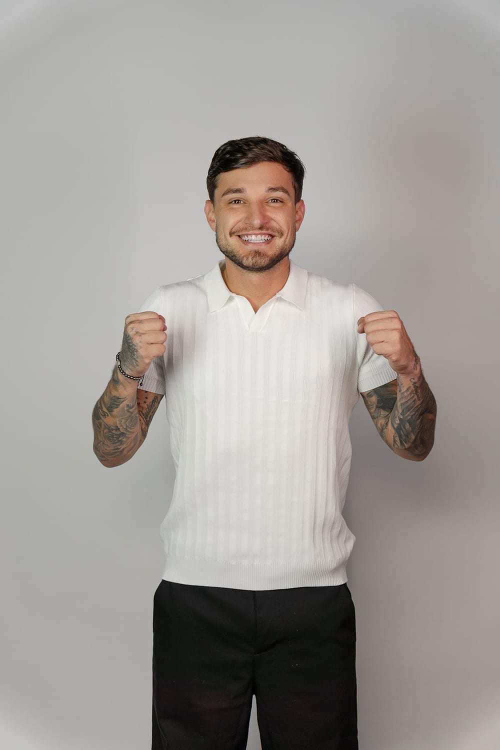 MC Gui sorrindo, de camisa polo branca, em estúdio